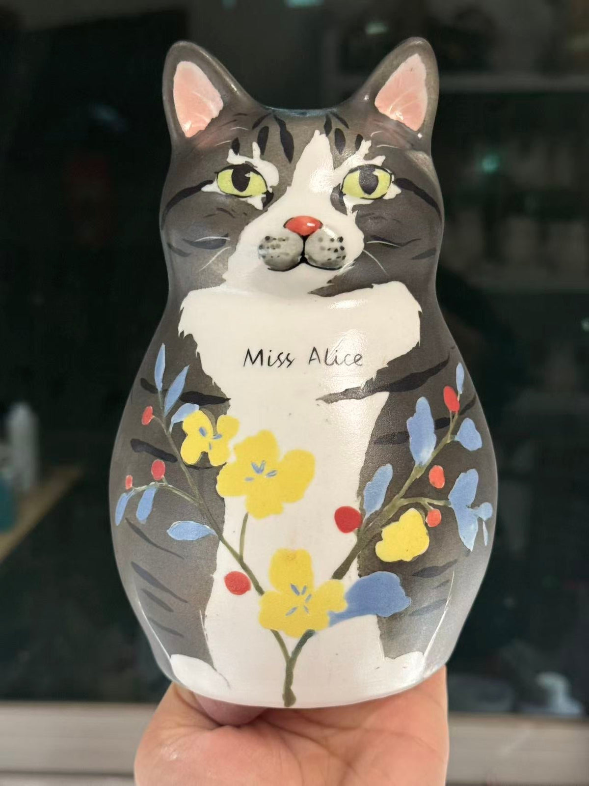 Grey tabby cat shaped ceramic with an irregular white chest, yellow flowers and Miss Alice lettering.