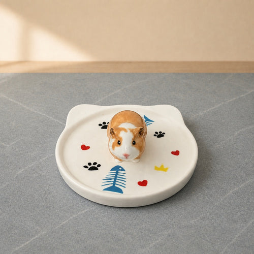 Tan and white guinea pig on a cat-face pet ring dish