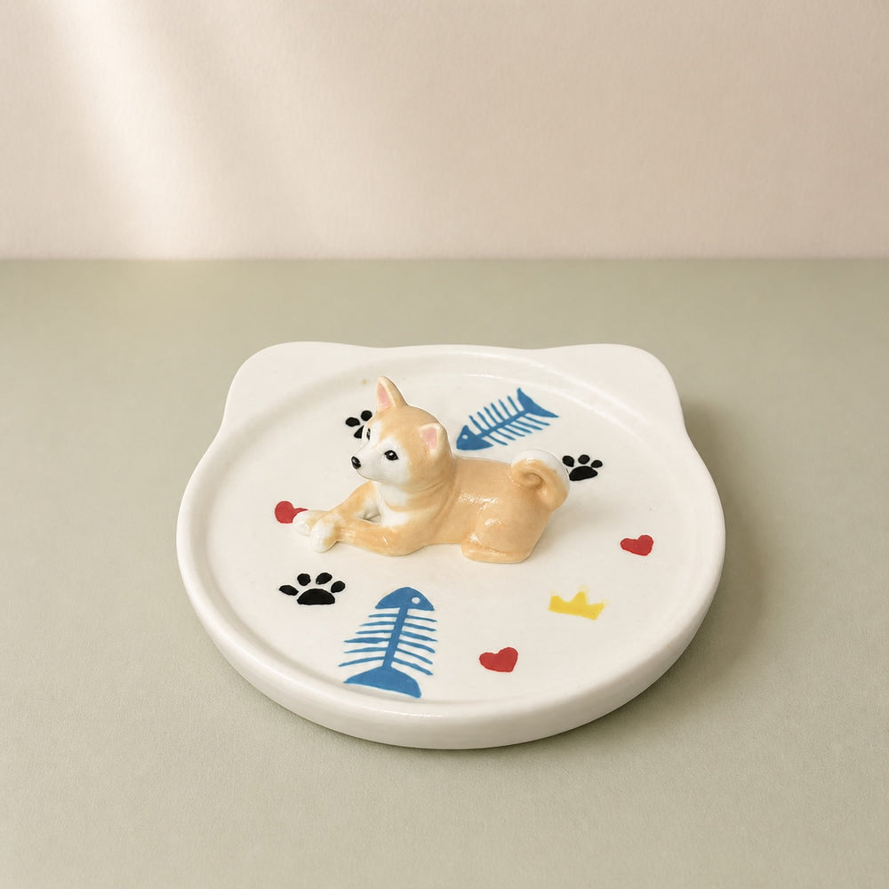 Tan and white Shiba dog on a cat-face pet ring dish