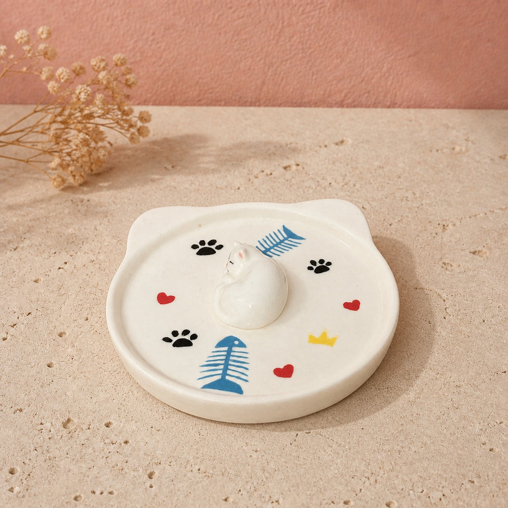 White sleeping cat on a cat-face pet ring dish view 2