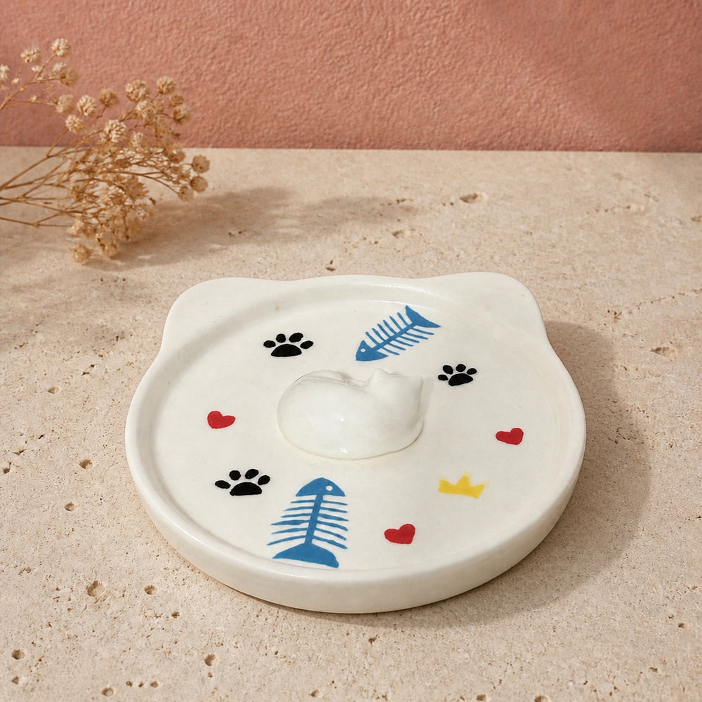 White sleeping cat on a cat-face pet ring dish view 3