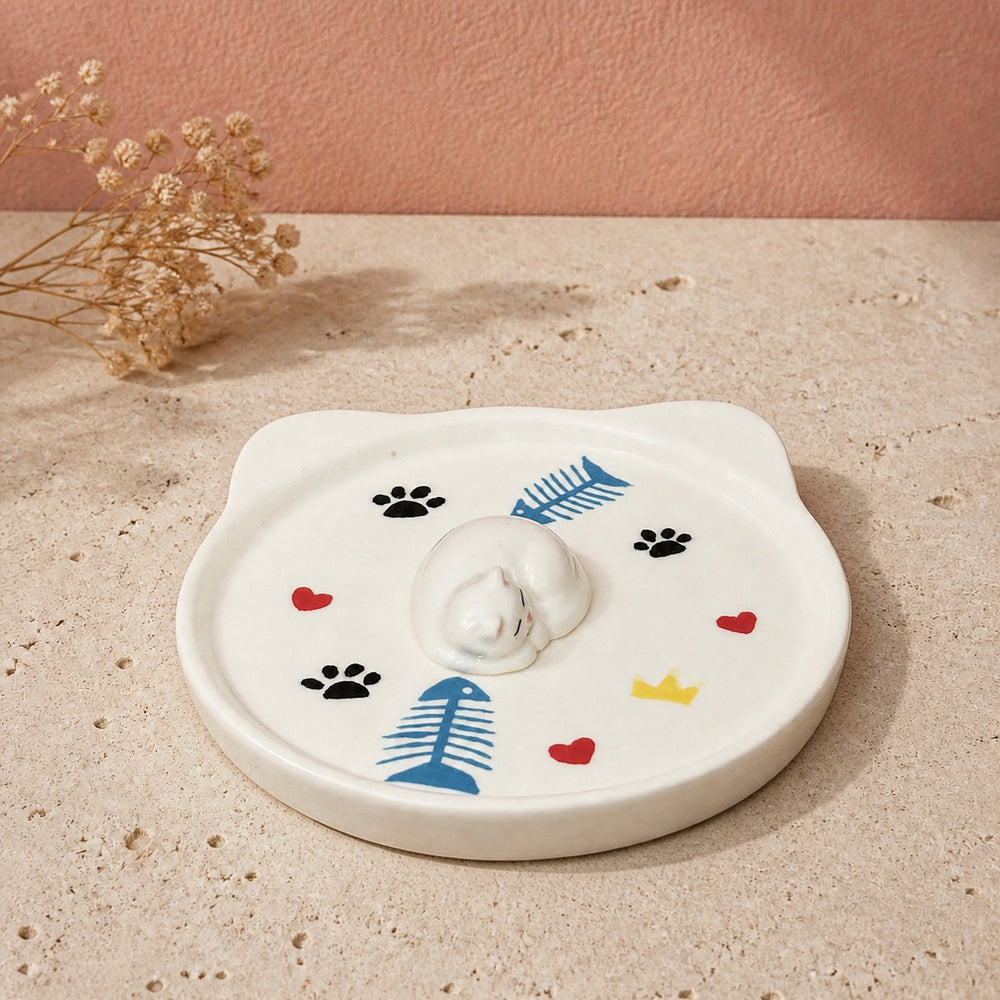 White sleeping cat on a cat-face pet ring dish view 4